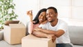 Happy black couple with house key and carton boxes looking at camera and smiling in their property, panorama Royalty Free Stock Photo