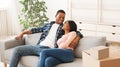 Happy black couple hugging on comfy couch in their new house after unpacking boxes with possessions, copy space Royalty Free Stock Photo