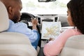 Happy black couple looking at paper map sitting inside car Royalty Free Stock Photo