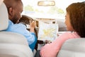 Happy black couple looking at paper map sitting inside car Royalty Free Stock Photo