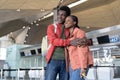 Happy black couple wait plane in airport. Young african man and woman smile hugging before flight