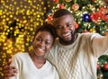 Happy black couple making selfie with Christmas tree on background