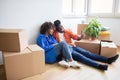 Happy black couple moving to new home, taking selfie among cardboard boxes Royalty Free Stock Photo