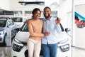 Happy Black Couple Posing With Car Keys In Hands In Dealership Center Royalty Free Stock Photo