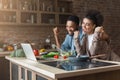 Happy black couple with raised arms cooking and looking on laptop Royalty Free Stock Photo