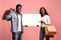 Happy black couple shopaholics holding empty board