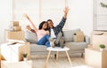 Happy black couple sitting on couch among cardboard boxes and lifting arms up, excited over moving to new home Royalty Free Stock Photo