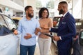 Happy Black Couple Talking To Salesman While Choosing Car In Dealership Center Royalty Free Stock Photo