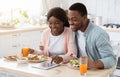 Happy Black Couple Using Digital Tablet While Having Breakfast In Kitchen Royalty Free Stock Photo