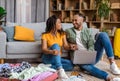 Happy black couple using laptop while planning vacation and booking hotel online sitting near unpacked suitcases Royalty Free Stock Photo