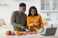 Happy Black Couple Watching Video Recipe On Laptop While Cooking In Kitchen Royalty Free Stock Photo