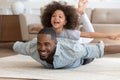 Happy black dad lying on floor with daughter on back. Royalty Free Stock Photo