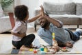 Happy black daddy and cute son playing with construction toy