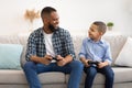 Happy Black Daddy And Son Playing Video Games At Home