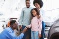 Happy black family buying new car, salesman giving them key at auto dealership Royalty Free Stock Photo