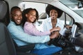 Happy black family buying new car, test driving automobile, smiling at camera in auto dealership Royalty Free Stock Photo