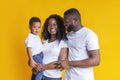 Happy black family with little son smiling and hugging on yellow background Royalty Free Stock Photo