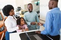 Happy black family paying for new car with credit card, buying auto from salesman at dealership store Royalty Free Stock Photo