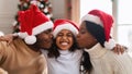 Happy black family in santa claus hats kissing, celebrating xmas Royalty Free Stock Photo