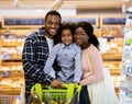 Happy black family with shopping cart purchasing food at supermarket Royalty Free Stock Photo