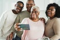 Happy black family taking a selfie with mobile phone inside kitchen at home - Main focus on mother face Royalty Free Stock Photo