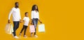 Happy black family of three walking with colourful shopping bags