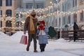Happy Black of father and child walking towards camera in winter and holding shopping bags Royalty Free Stock Photo