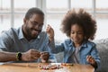 Happy Black father and daughter girl making decoration together