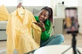 Happy black female blogger making video review with new clothes after successful shopping, recording video on cellphone Royalty Free Stock Photo