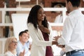 Happy proud black female employee get rewarded handshake caucasian boss