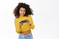 Happy Black girl playing games on mobile phone, using smartphone, standing over white background Royalty Free Stock Photo