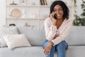 Happy black girl talking on mobile phone, relaxing on couch at home Royalty Free Stock Photo