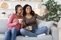 Happy black girls besties taking selfie together at home