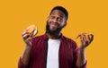 Happy Black Guy Holding Burger And Pizza On Yellow Background