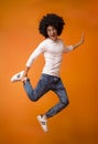 Happy black guy jumping on orange studio background