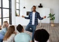 Happy black guy showing pantomime to his multiracial friends, playing charades guessing game at home Royalty Free Stock Photo