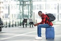 Happy black guy sitting on bag at train station Royalty Free Stock Photo