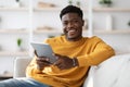 Happy black guy using digital tablet at home Royalty Free Stock Photo