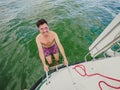 Happy black hair man down the ladder into the water. A man down into the water on an iron ladder on the sailing yacht a to swim Royalty Free Stock Photo