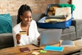 Happy black lady booking vacation at travel agency or making hotel reservation online, using laptop and credit card Royalty Free Stock Photo