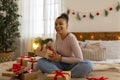 Happy black lady writing greeting cards for her family members, sitting on bed among wrapped Christmas gift boxes Royalty Free Stock Photo