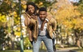 Happy black man carrying his girlfriend on back in autumn park Royalty Free Stock Photo