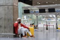 Happy black man in casual clothes with smile sitting near wall and answering phone call at airport. Royalty Free Stock Photo