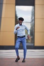 Happy black man dancing on city street near building, smiling and wearing formal clothes blue trousers and shirt Royalty Free Stock Photo