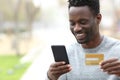 Happy black man paying online with credit card on phone Royalty Free Stock Photo