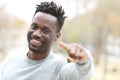 Happy black man pointing and looking camera in a park Royalty Free Stock Photo