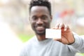 Happy black man showing blank credit card in the park