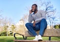 Happy black man talking on smart phone sitting in a park on a sunny day. Royalty Free Stock Photo