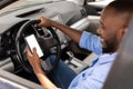 Happy black man using smartphone with empty screen driving car