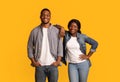 Happy black man and woman in denim clothes posing over yellow background Royalty Free Stock Photo